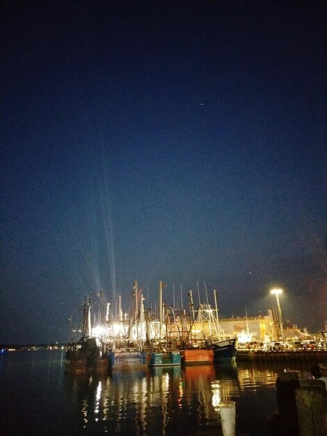 Sailboats moored in harbor against clear sky at night