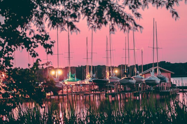 Sailboats moored in lake against sky at sunset