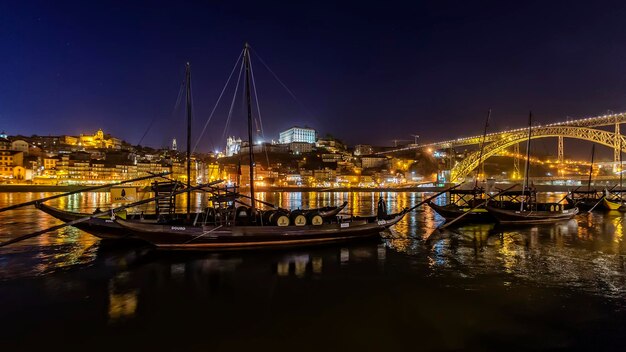 Foto barche a vela ormeggiate sul fiume dalla città illuminata contro il cielo notturno