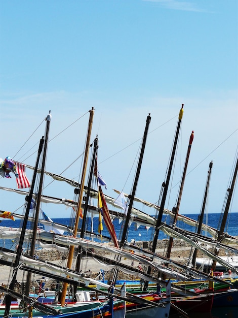 Sailboats moored in sea against blue sky