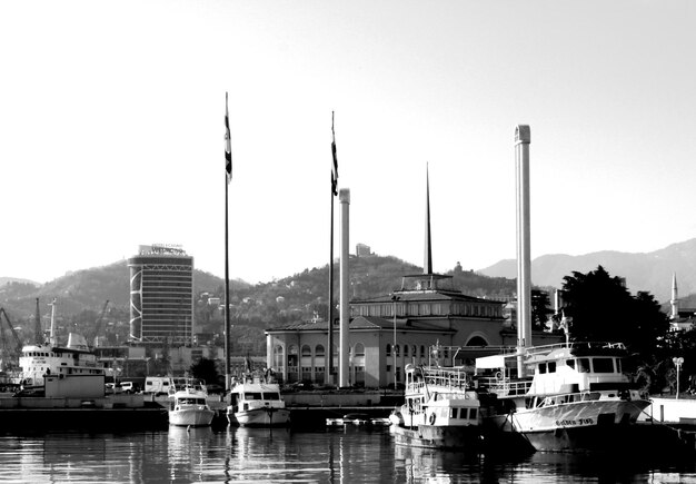 Sailboats in river by buildings against sky