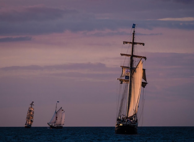 Sailboats sailing in baltic sea against sky during sunset