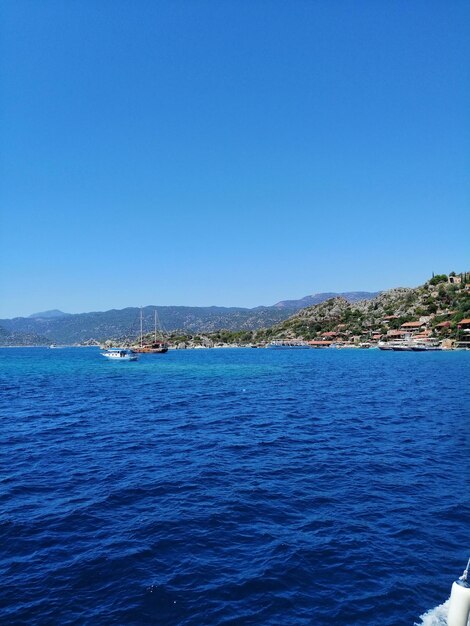 Sailboats sailing in sea against clear blue sky