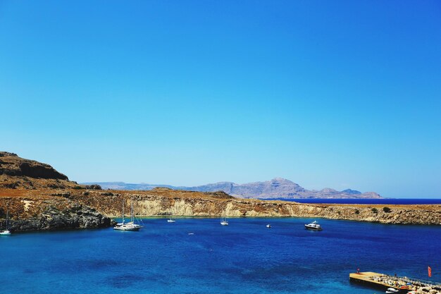 Sailboats in sea against clear blue sky