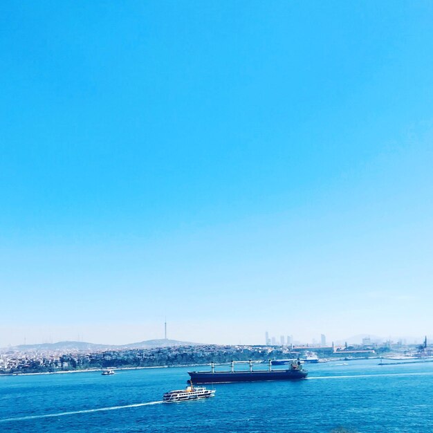 Sailboats in sea against clear blue sky