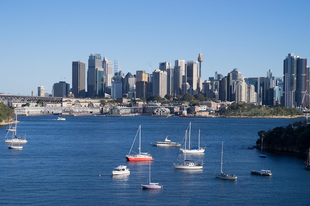 Sailboats in sea by buildings against clear sky