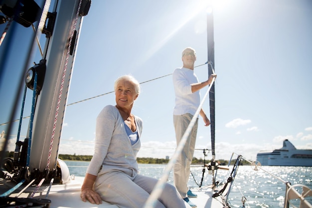 Foto concetto di vela, età, turismo, viaggi e persone - coppia senior felice che si abbraccia sulla barca a vela o sul ponte dello yacht che galleggia nel mare