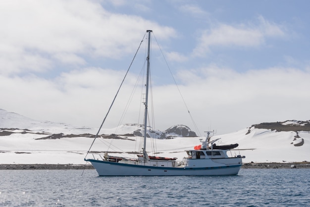 Sailing yacht and iceberg in antarctic sea