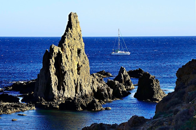 Sailing Yacht near Rocky Coastal Formations at Sea