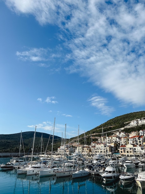 Sailing yachts stand off the coast with colorful villas at the foot of the mountains