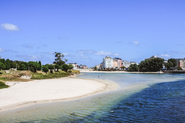 Foto villaggio e spiaggia del marinaio un giorno soleggiato, san ciprian, san cibrao, galizia, spagna