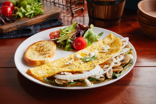 Rotolo di frittata sailorman con insalata servita in un piatto isolato su sfondo di legno vista laterale