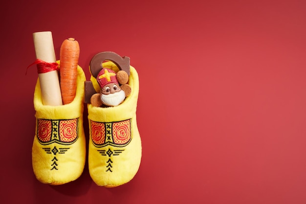 Saint nicholas  sinterklaas day with shoe carrot and traditional sweets on red background