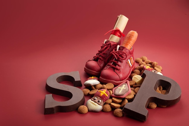 Saint nicholas  sinterklaas day with shoe carrot and traditional sweets on red background