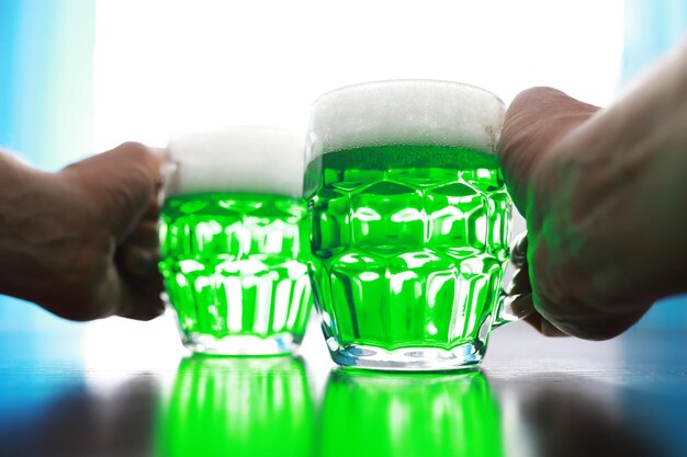 Saint patrick\'s day holiday. national irish holiday. green\
beer. hand with a mug of emerald beer in a bar.