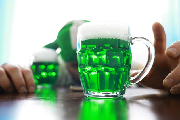 Saint Patrick's Day holiday. National Irish holiday. Green beer. Hand with a mug of emerald beer in a bar.