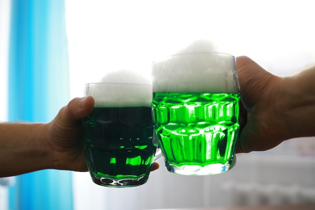 聖パトリックの日の休日国民のアイルランドの休日緑色のビールバーでエメラルドビールのマグカップと手