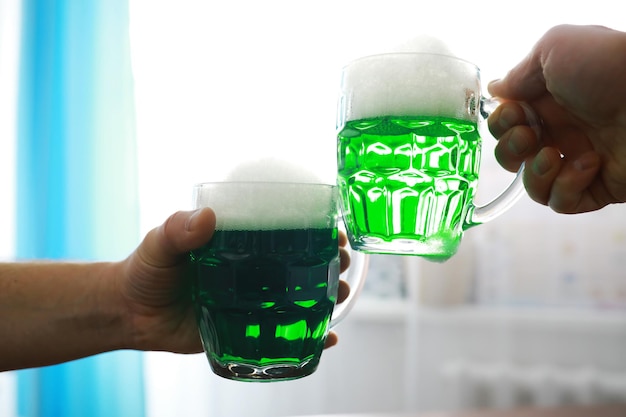 Saint Patrick's Day vakantie. Nationale Ierse feestdag. Groen bier. Hand met een mok smaragdgroen bier in een bar.