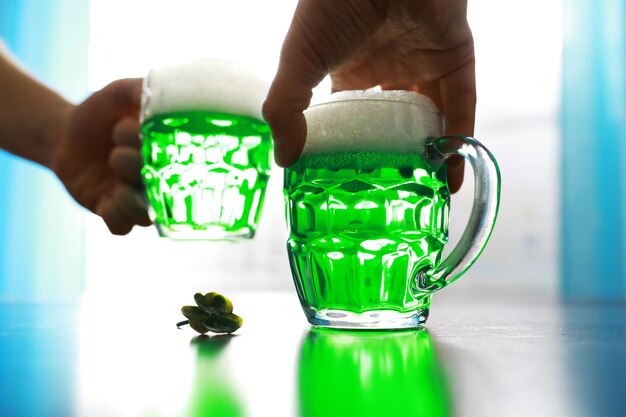 Saint patricks day holiday national irish holiday green beer\
hand with a mug of emerald beer in a bar