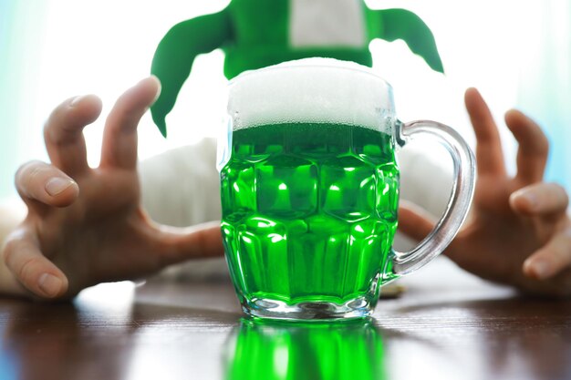 Saint patricks day holiday national irish holiday green beer\
hand with a mug of emerald beer in a bar