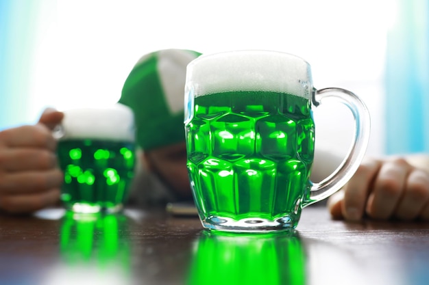 Saint patricks day holiday national irish holiday green beer\
hand with a mug of emerald beer in a bar