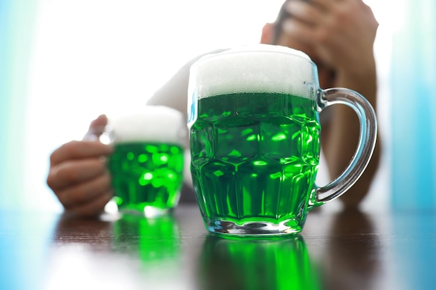 Saint patricks day holiday national irish holiday green beer\
hand with a mug of emerald beer in a bar