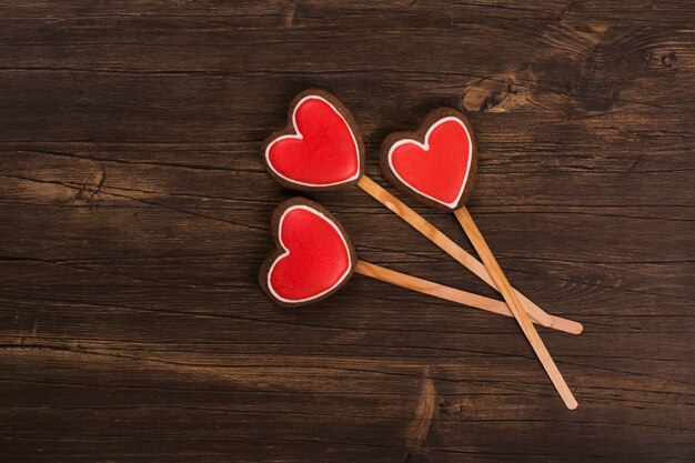 Saint Valentine card. Three heart shaped gingerbreads over rustic wooden background. Top view