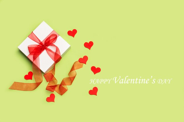 A saint valentine s gift and paper red hearts on a green background