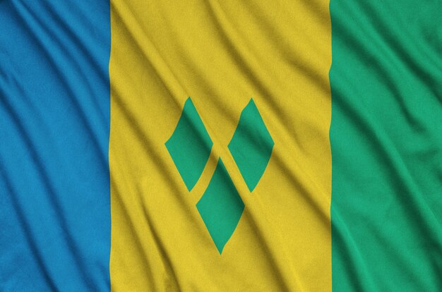 Saint vincent and the grenadines flag  is depicted on a sports cloth fabric with many folds.