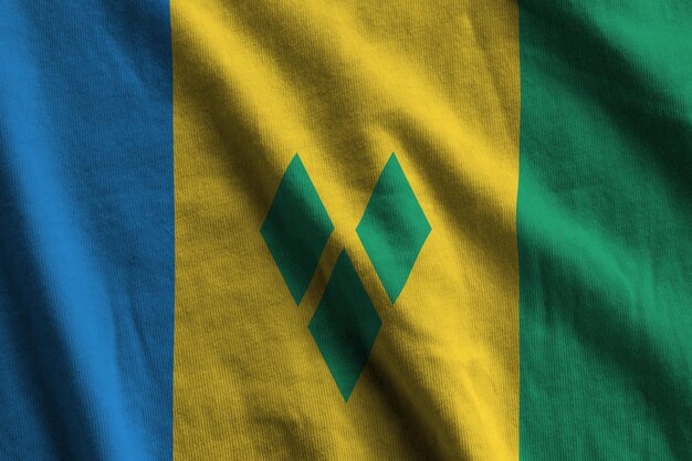 Флаг Сент-Винсента и Гренадин с большими складками, развевающимися под студийным светом в помещении Официальные символы и цвета на баннере