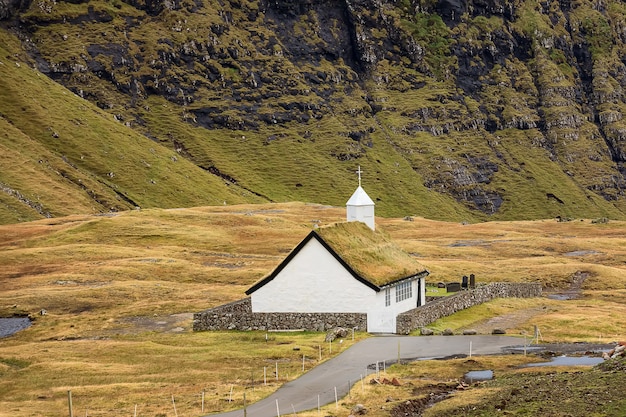 Церковь саксунар киркья и горы возле деревни саксун, фарерские острова, дания