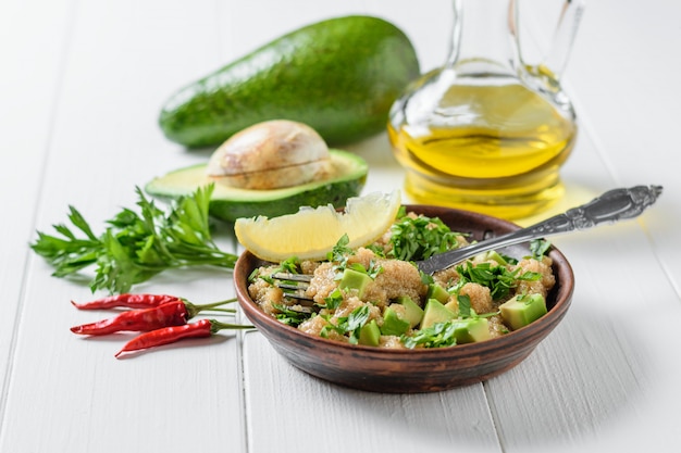 Salad of amaranth seeds, avocado and parsley with olive oil on a table.