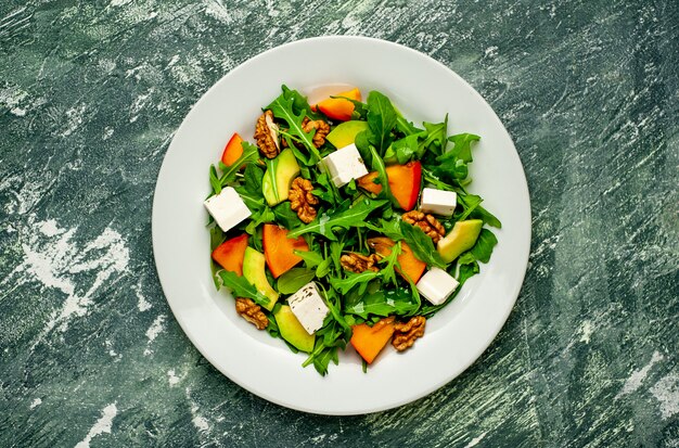 Insalata di rucola, formaggio, barbabietola, noce, sullo sfondo di ardesia, pietra o cemento.