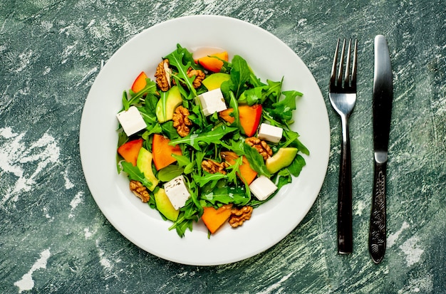 Salad of arugula, cheese, beet, walnut, on the background of slate, stone or concrete.