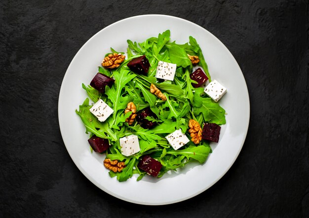 Salad of arugula, cheese, beetroot, walnut, on a background of slate, stone or concrete.