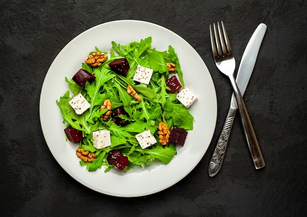 Salad of arugula, cheese, beetroot, walnut, on a background of slate, stone or concrete.