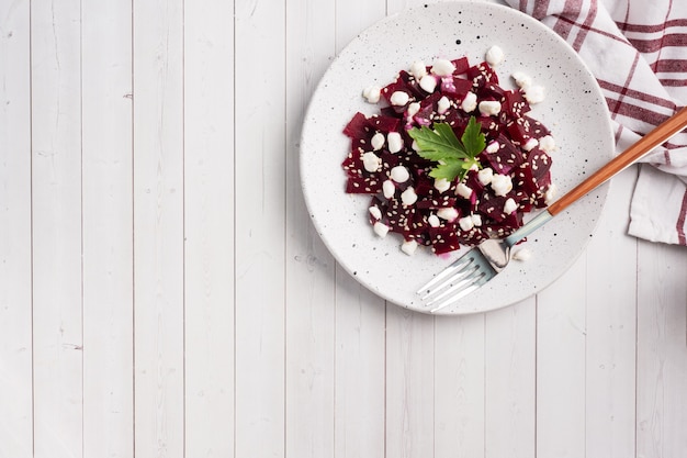 Salad of boiled beetroot and grain curd with sesame seeds on a plate.