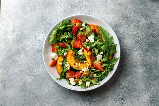 Salad bowl with arugula, strawberry, cottage cheese, nectarine and peanut paste. healthy eating concept