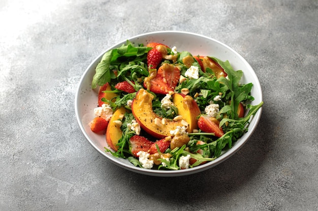 salad bowl with arugula, strawberry, cottage cheese, nectarine and peanut paste. healthy eating concept