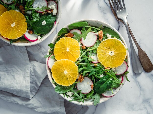 Foto ciotola di insalata con arance, spinaci, arugula, radice