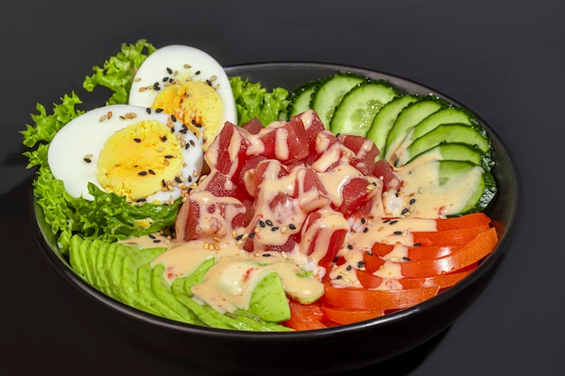 Foto ciotola di insalata con tonno, riso, pomodori, cetrioli e uova bollite di avocado