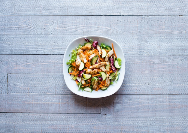 Insalata di petto di pollo con zucchine e pomodorini, su una superficie di legno