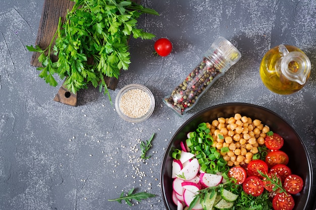 Salad of chickpeas, tomatoes, cucumbers, radish and greens. Dietary food. Vegan salad. Top view. Flat lay. Buddha bowl