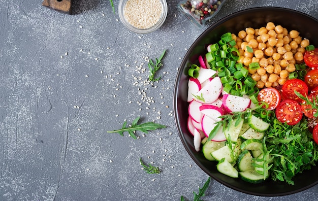 Salad of chickpeas, tomatoes, cucumbers, radish and greens. Dietary food. Vegan salad. Top view. Flat lay. Buddha bowl