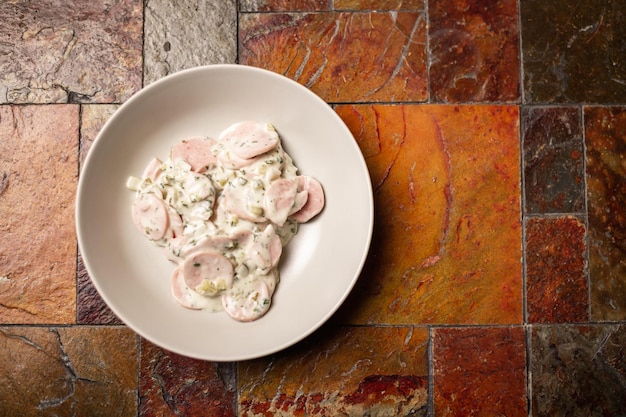 みじん切りソーセージ グリーンとサワー クリームのサラダ 石の背景に皿にシンプルな肉のサラダ