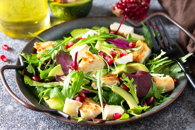 Salad closeup with grilled chicken avocado brie cheese arugula and pomegranate