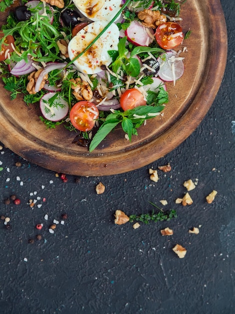 Salad on cutting board  softboiled egg cherry tomatoes arugula parsley mint walnuts cheese