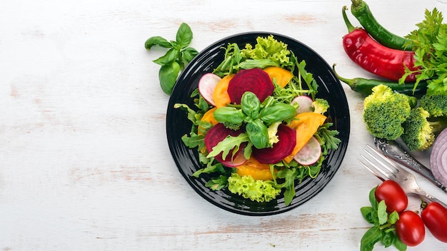 Salad of fresh beets tomatoes and lettuce Healthy food On a white wooden table Top view Free space for text