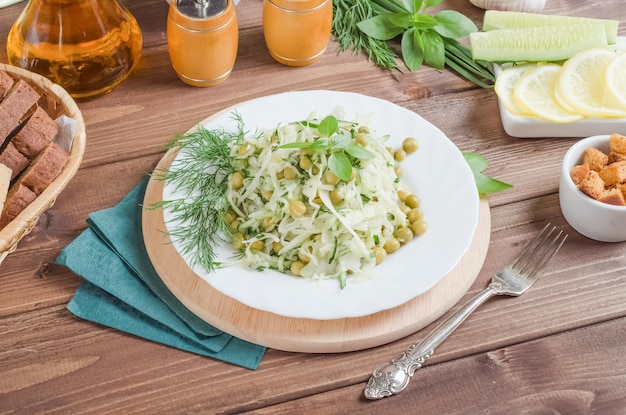 Foto insalata di cavolo cappuccio fresco e piselli con erbe aromatiche in un piatto bianco su fondo di legno scuro