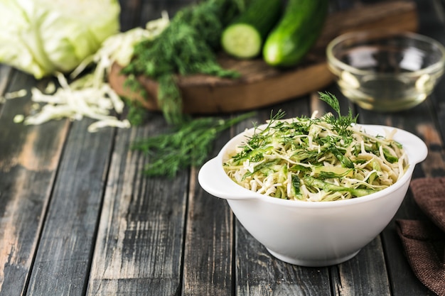 Salad of fresh fermented cucumbers and cabbage on a dark wood.